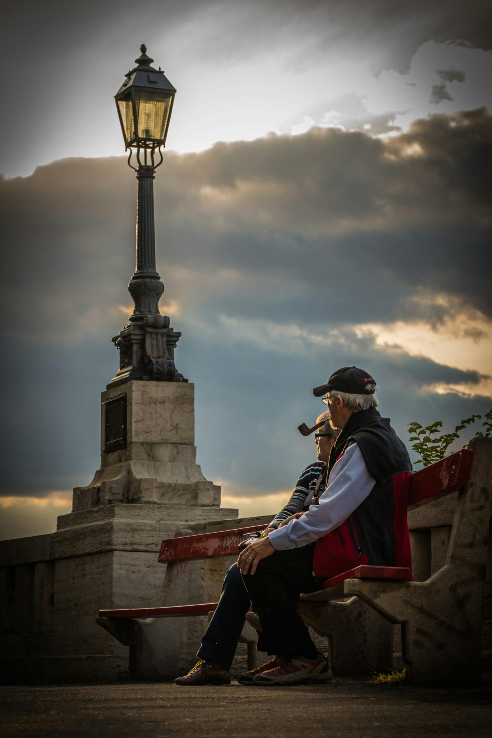 Seniors enjoying a quiet moment on a park bench during a serene sunset.